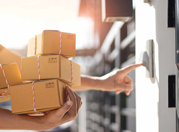 Photo of a delivery person holding packages and ringing a doorbell.