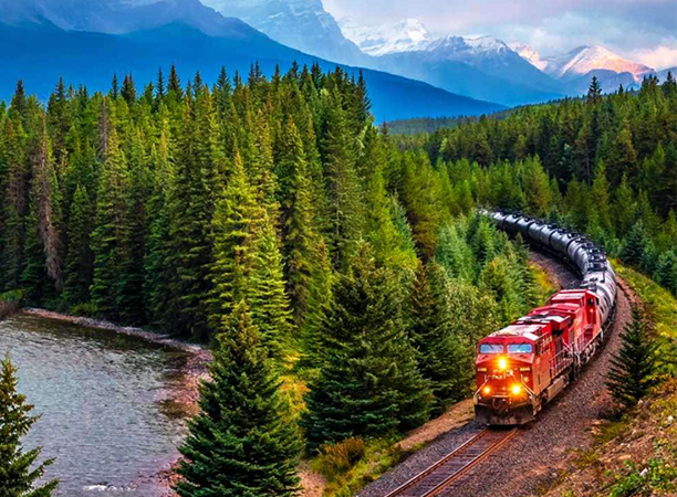 A digitally-managed train on a track in the mountains near a river.