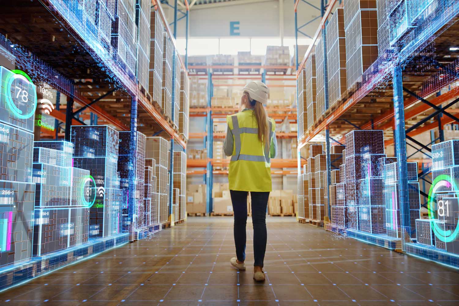 Photo of a woman wearing a hard hat and safety vest walking in an aisle of a warehouse. The inventory in the warehouse is overlaid with graphics depicting inventory management apps.