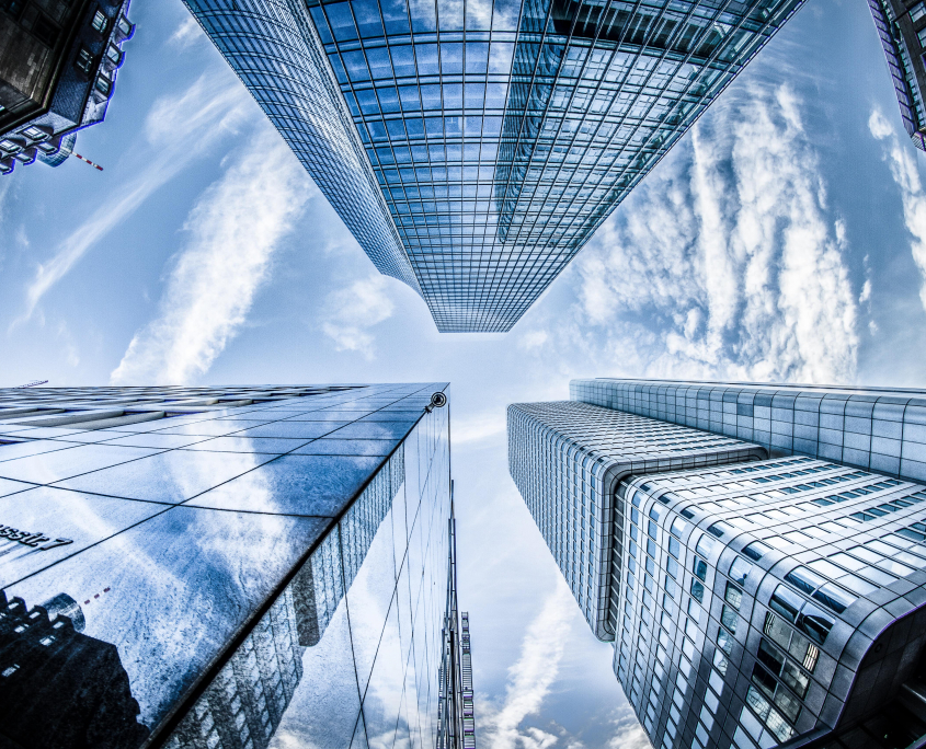 Photo of four glass skyscrapers from the view of someone standing on the ground between them looking up.